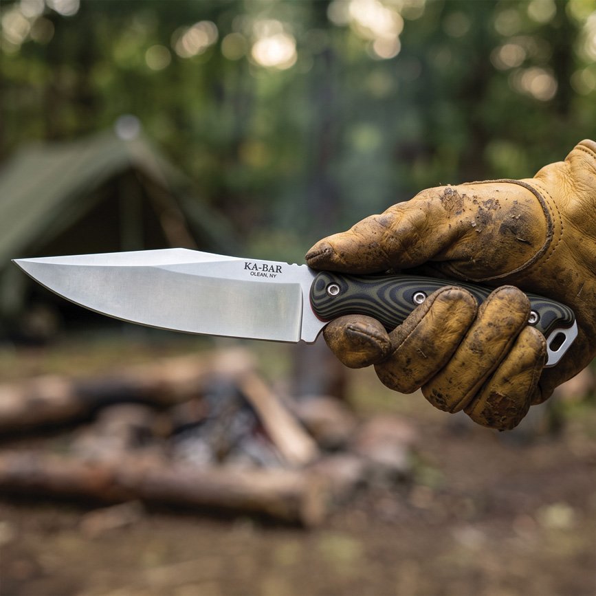 KA-BAR Becker BK25C Outpost knife in hand at a campsite, real manufacturer photo